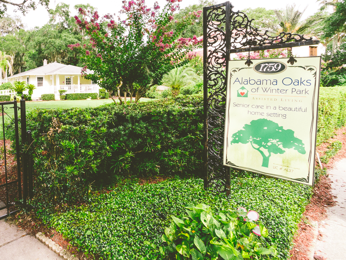 Assisted living entrance sign with a yellow residence and landscaped yard in Winter Park.