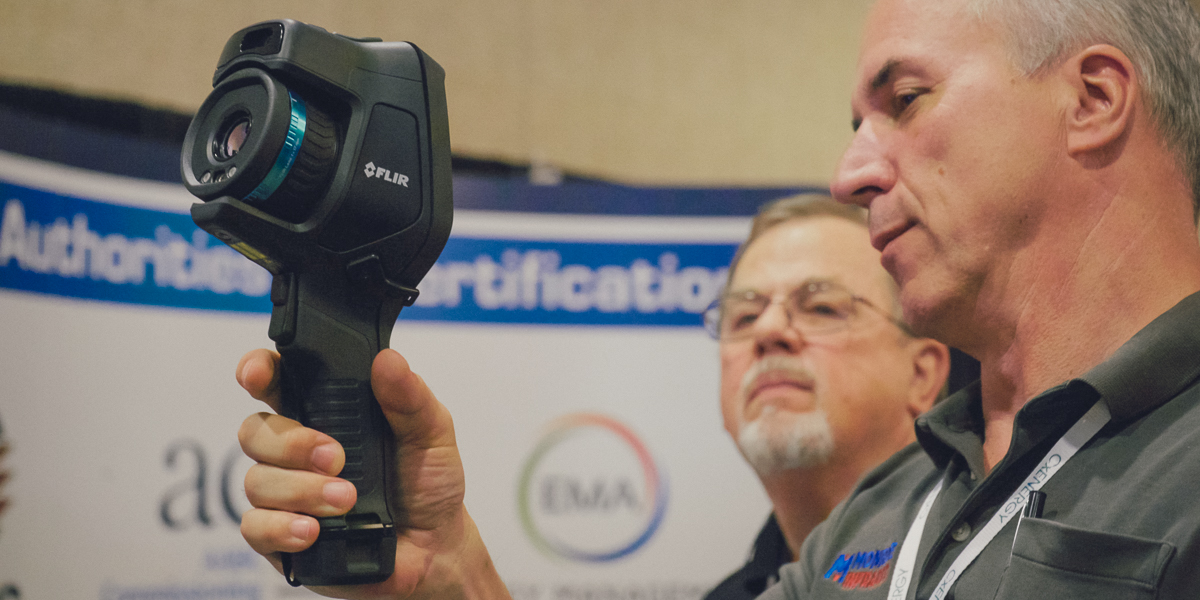 Two men examine a thermal imaging camera at cxenergy conference in omni orlando resort at championsgate