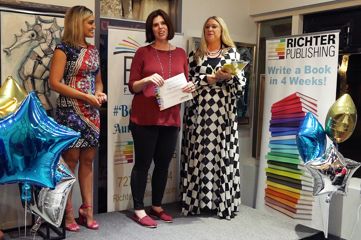 Three women presenting award at book publishing event