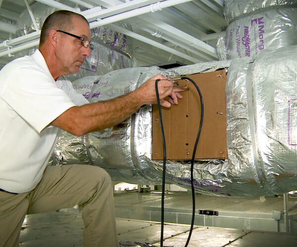 Technician installing insulation in commercial hvac ductwork