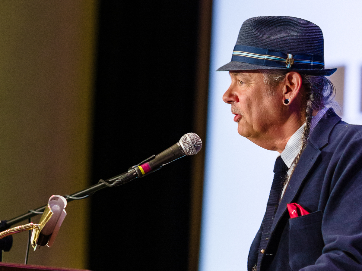Man in hat speaking at conference podium