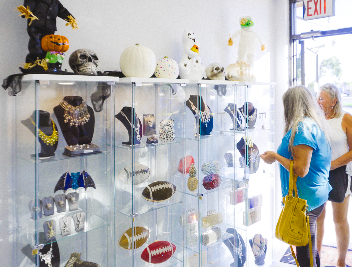 Customers browsing jewelry in a bright boutique decorated for halloween.