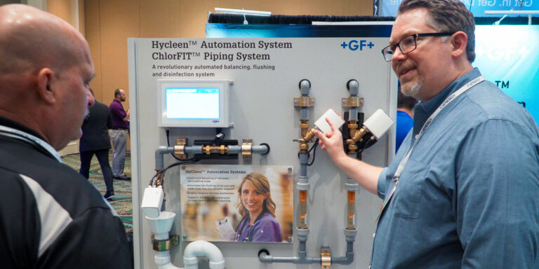 Attendees discussing an automation system display at an energy industry conference at Caribe Royale Orlando.