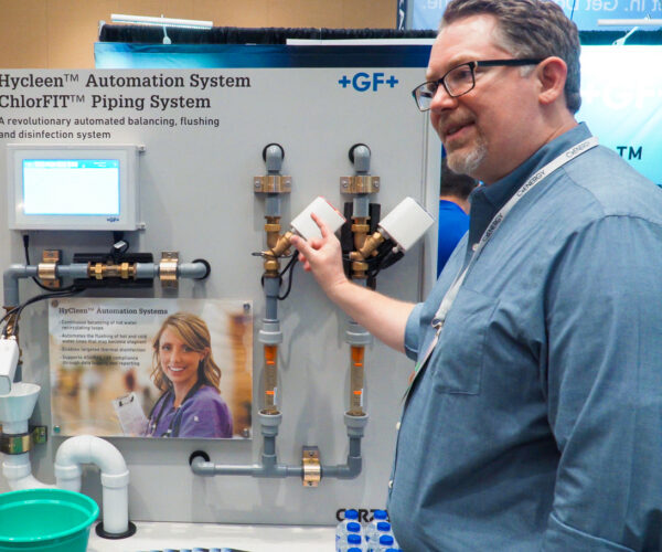 Man presenting hyclean automation system at trade show.