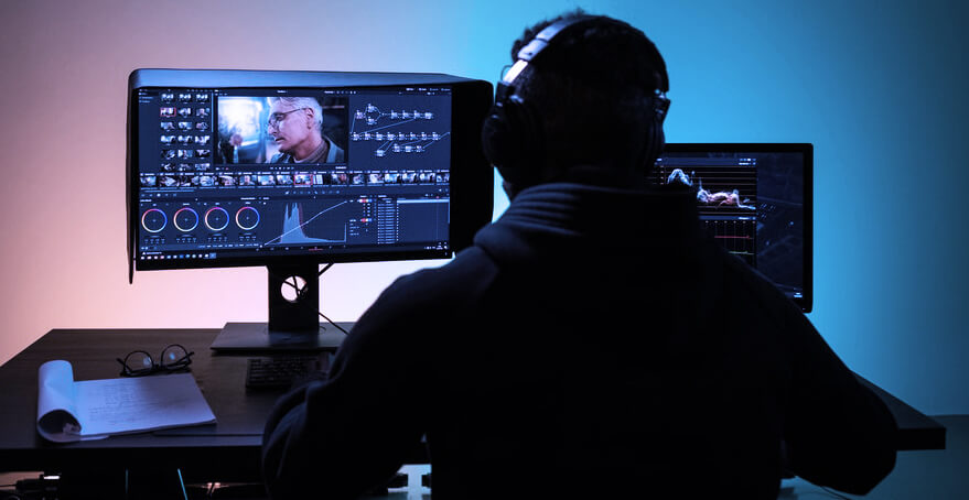 Video editor working at dual monitors in a color grading suite