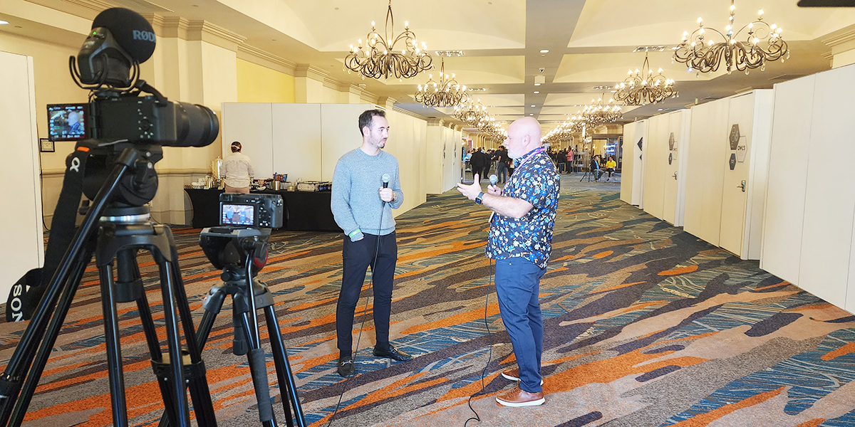 An interview is filmed in a rosen shingle creek hallway, with one person holding a microphone and a tripod-mounted camera capturing the scene.