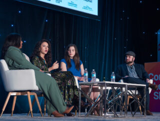 Four people participating in a panel discussion onstage at a conference.