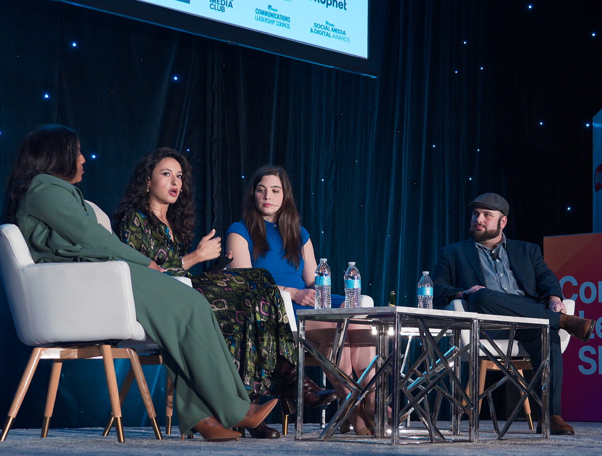 Four people participating in a panel discussion onstage at a conference.