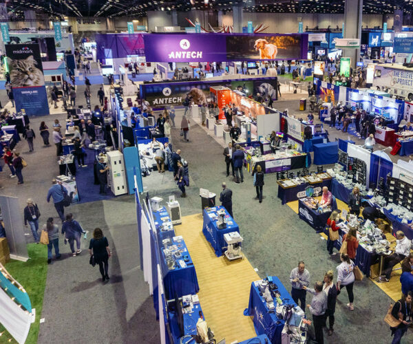 Crowded trade show floor with exhibitors and attendees