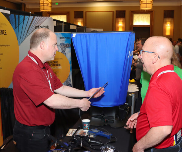 Two men conversing at a tech conference booth