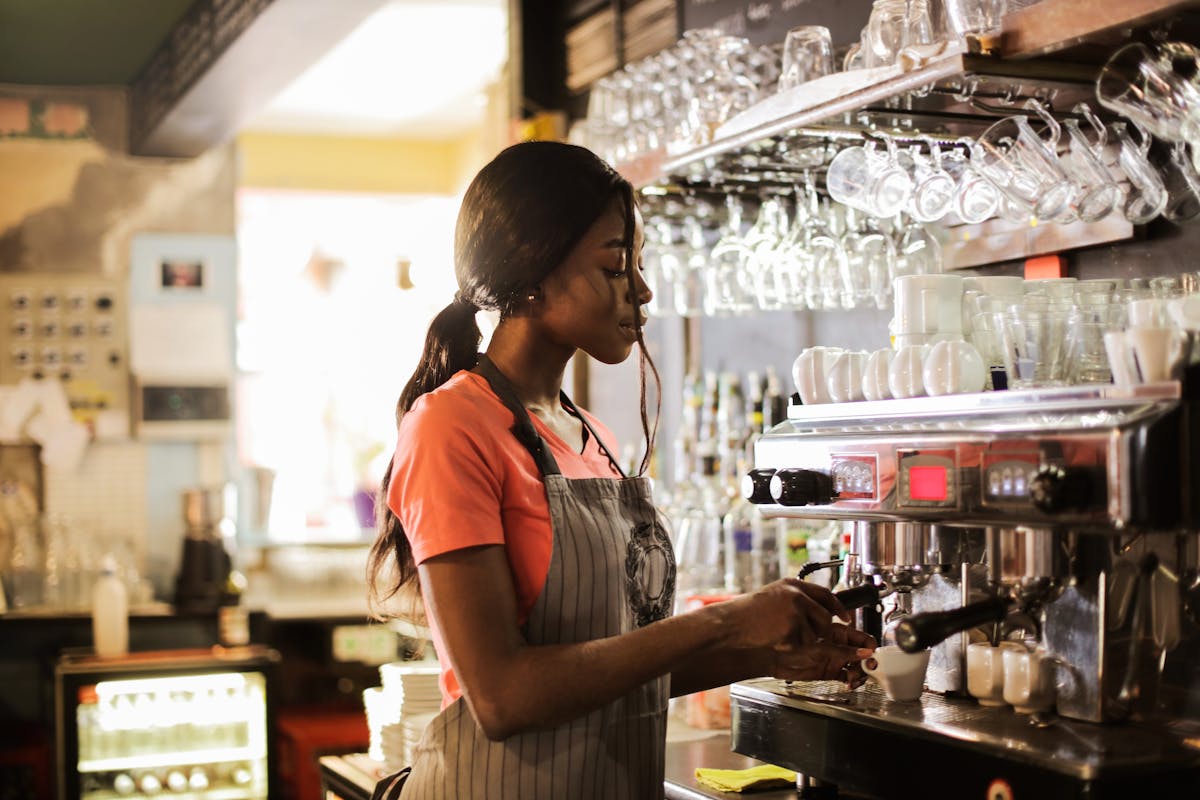 Woman preparing coffee latte near espresso machine