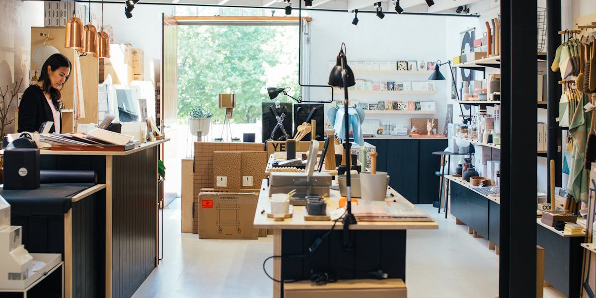 Young ethnic female employee standing at counter in creative gift shop