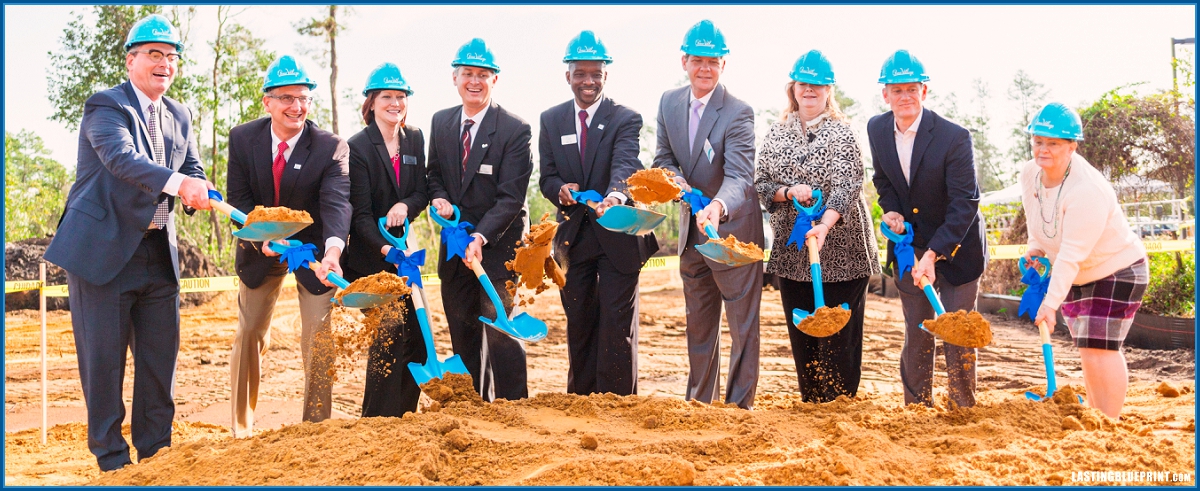 An orlando event video production company captures a group in suits and hard hats at the quest village groundbreaking, each holding a shovel with sand.