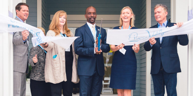 Group cutting a ribbon during a community center grand opening ceremony.