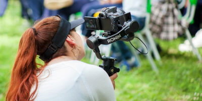 Event videographer using a gimbal-mounted camera outdoors.