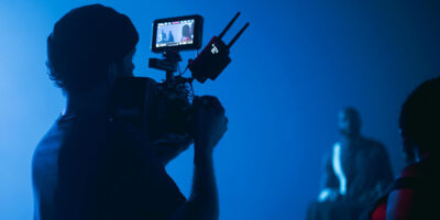 Videographer filming a subject in a blue-lit production setting