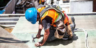 Construction worker in safety gear fastening material on a work site.