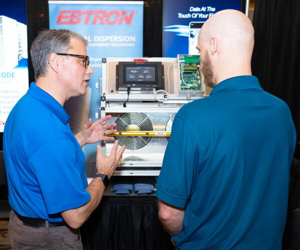 Two professionals speaking at an exhibitor booth during cxenergy 2025 in charlotte. Photo by lance omar photography.