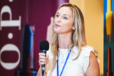 Woman speaking at a business seminar at jw marriott grande lakes in orlando, with colorful branding in the background.