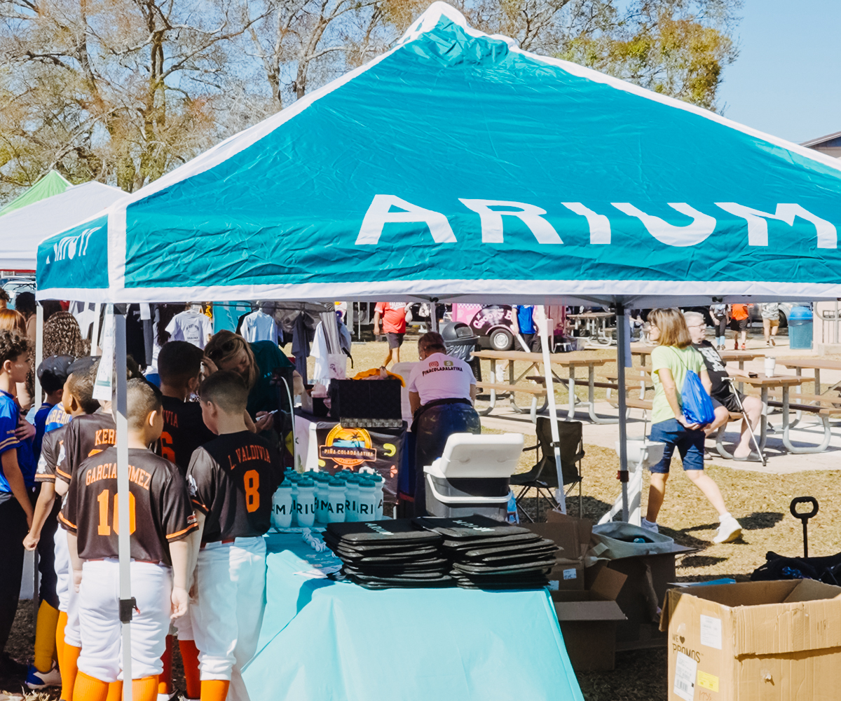 Children interacting at a sponsor booth during a youth baseball opening-day event in Orlando.