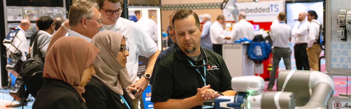 Expo exhibitor demonstrating a robotic system to attendees at a booth during an event at coronado springs in orlando