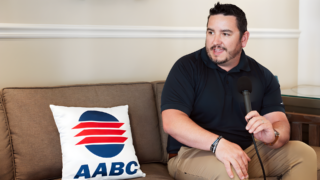 Man seated with a handheld microphone during a professional career interview.