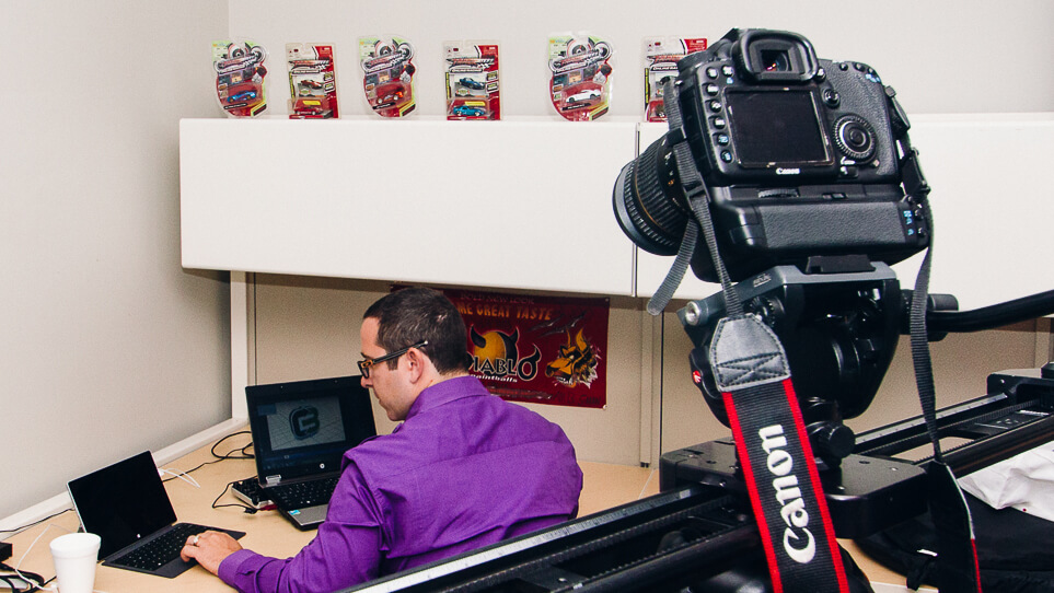 Camera on a slider filming a man working at a desk during corporate video production