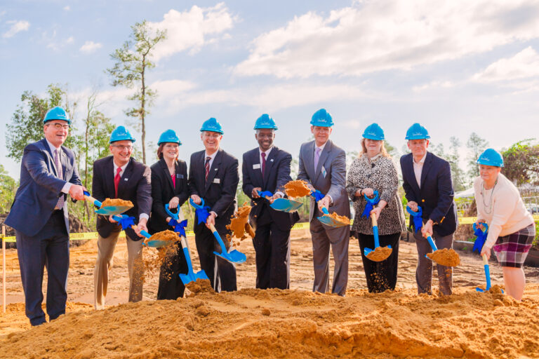 Group posing with shovels and hard hats at an Orlando groundbreaking ceremony