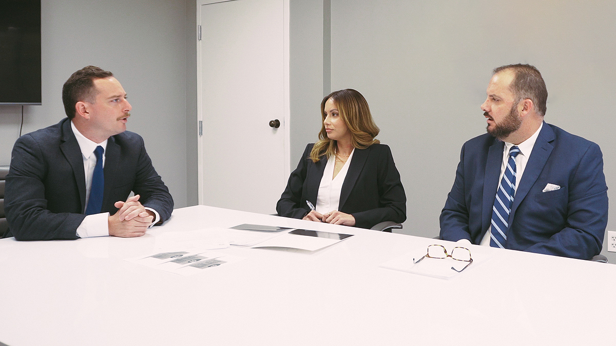 Three attorneys seated around a conference table during a law firm meeting in orlando.