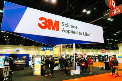 Wide view of an industrial safety trade show booth with attendees at the Orange County Convention Center.