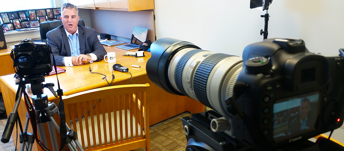 Two-camera corporate video interview setup filming an executive in an office.