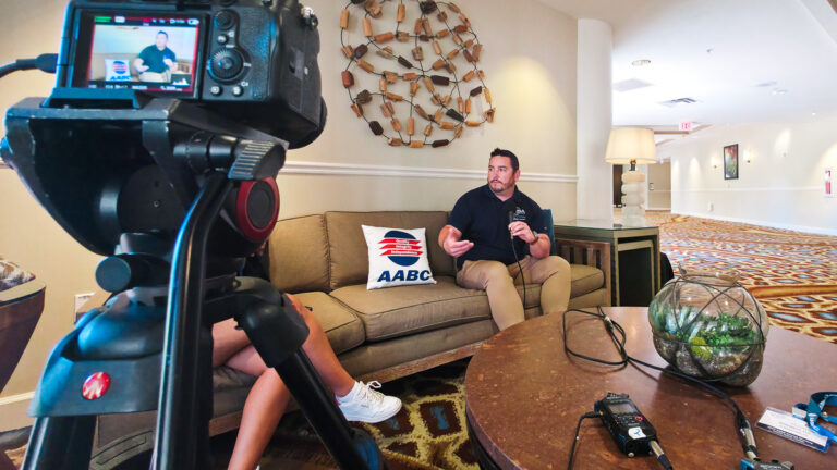 Mirrorless camera on a tripod recording an AABC member interview, with an audio recorder on the table at Omni Amelia Island Resort & Spa.
