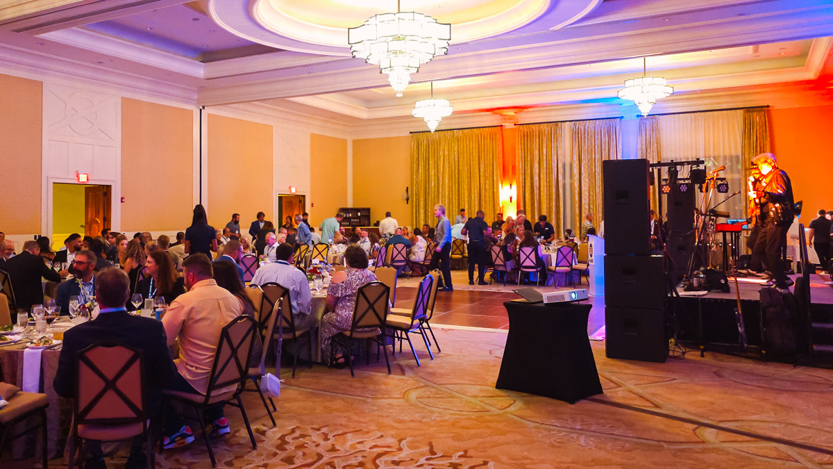 Attendees seated at dinner tables while a musician performs during the 2026 AABC Annual Meeting Closing Celebration.