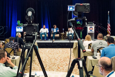 Two cameras recording a panel discussion at the 2026 AABC Annual Meeting.