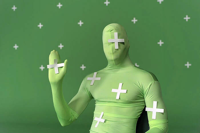 Man sitting on chair waving during green screen video production project.